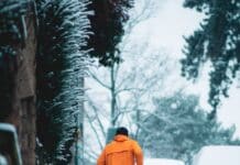 심장병 예방을 위한 스트레스 관리법 person in orange hoodie walking on snow covered pathway during daytime
