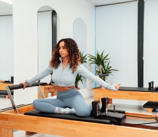 필라테스로 몸매 교정이 가능할까? a woman sitting on a piyor in a room