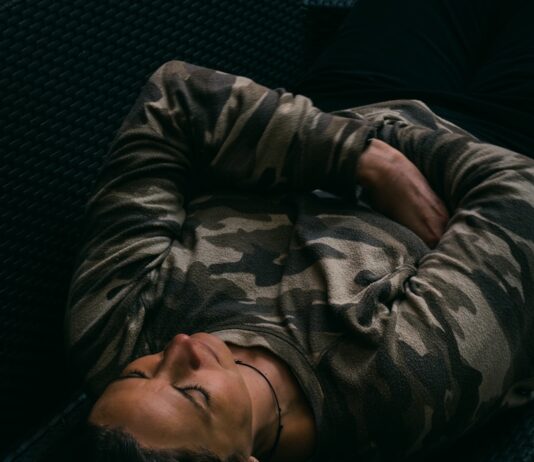 수면, 건강의 열쇠…잠을 잘 자야 몸과 마음이 산다 woman in gray and black camouflage jacket lying on black couch