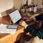 “마음도 챙기는 시대, 디지털 디톡스가 불러온 건강 습관 변화” Person working on laptop at a wooden desk.
